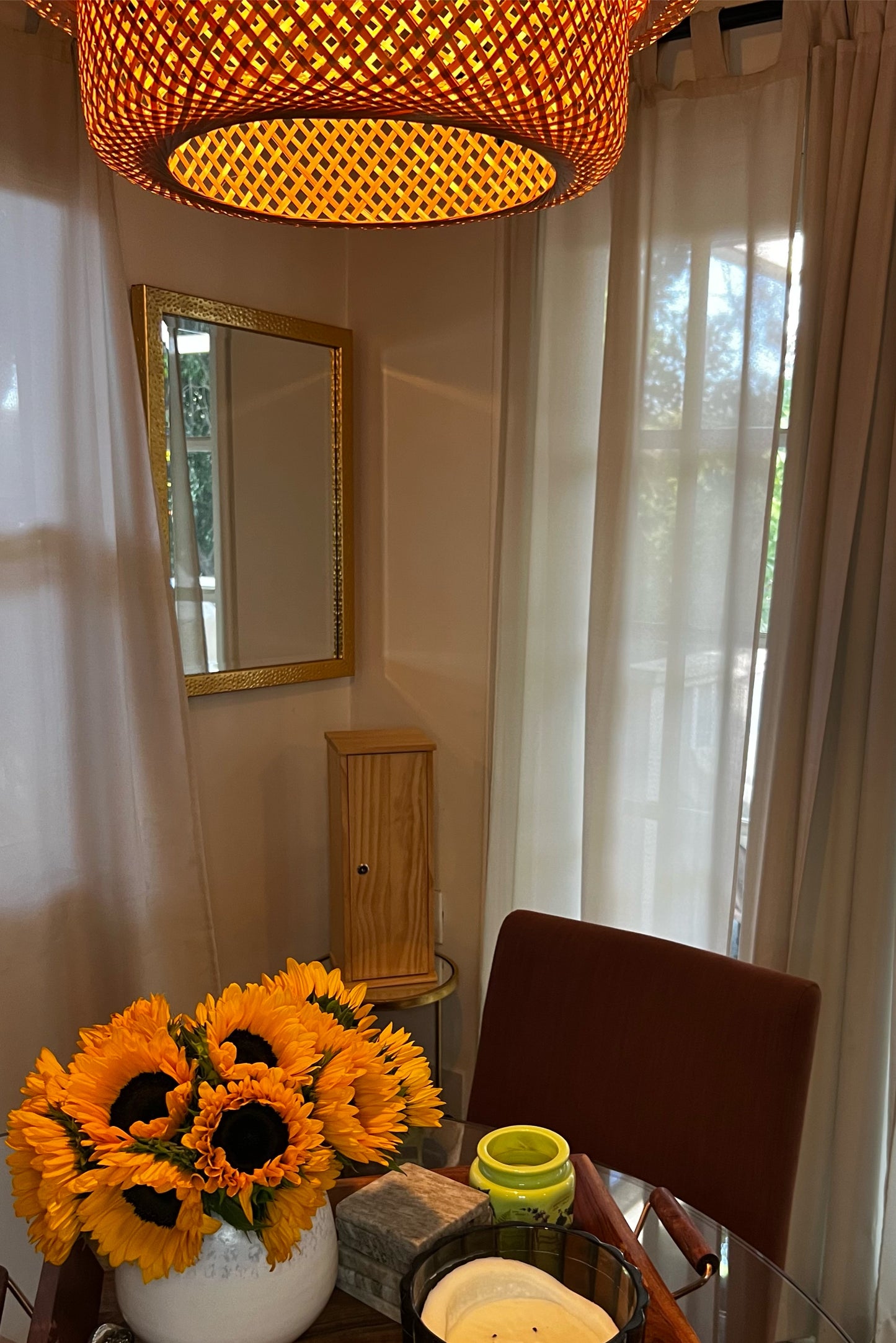 Dining room with sunflowers in a vase, wooden chair, and lampshade.